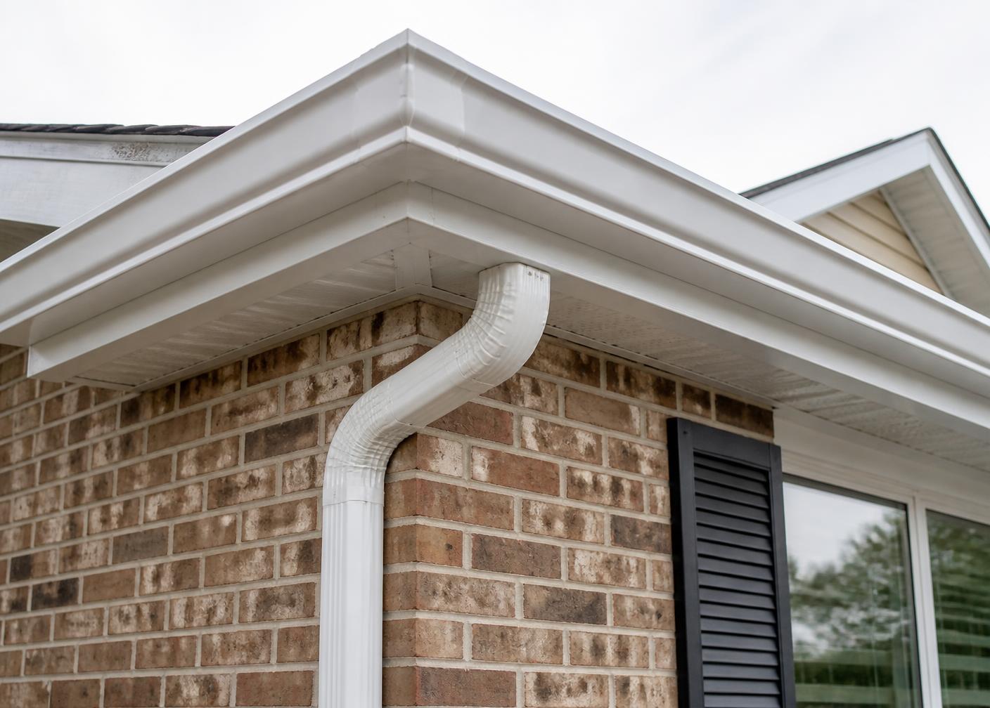 White seamless K-style gutter and downspout on a brick home